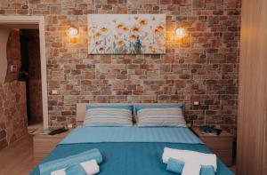 una camera con letto blu e parete in mattoni di Amélie Casa Vacanze a Santa Croce Camerina