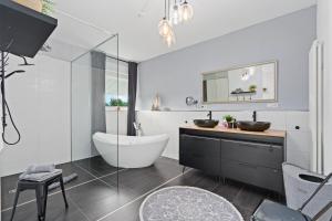 ein Badezimmer mit Badewanne, Waschbecken und Spiegel in der Unterkunft ANYTIME - Rohrbach Apartments in Friedrichshafen