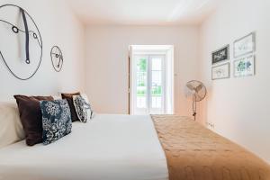 1 dormitorio con 1 cama blanca con almohadas y ventilador en Lisbon Prime Apartment, en Lisboa