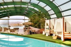 una piscina con sedie, tavoli e un soffitto in vetro di Arrecife Gran Hotel & Spa ad Arrecife