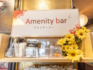 una señal para un bar de aniversario con flores en un estante en Omotenashi Hostel Miyajima, en Hatsukaichi