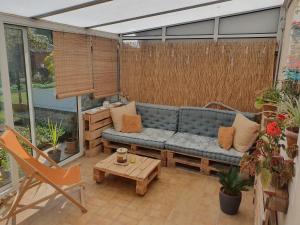 - une terrasse avec une moustiquaire, un canapé et une table dans l'établissement Maison Zen proche circuit, au Mans