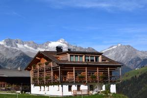 een groot houten huis met bergen op de achtergrond bij Schüsslerhof in Campo Tures
