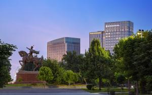 uma estátua num parque em frente a alguns edifícios em InterContinental Tashkent, an IHG Hotel em Tashkent