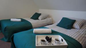 two beds with green and white sheets with cups and mugs at Domy całoroczne Osada na Górce in Ustrzyki Dolne