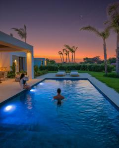 um homem numa piscina numa casa em TAF Beach Villas with Tesla em Tigaki