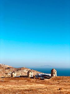a building on a hill with the ocean in the background at Rustic Stone House in the Heart of Folegandros in Áno Meriá