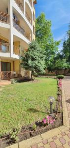 een gebouw met een tuin met roze bloemen ervoor bij Golden Dreams Apartment in Sunny Beach