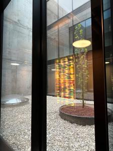 uma janela com vista para um edifício com uma árvore num pátio em Boulderbar Hotel Leonding em Linz