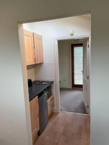 an empty kitchen with a door open to a hallway at Self catering apartment at Beechwalk House. in Enniskerry