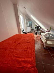 1 dormitorio con cama roja, mesa y sillas en ALYANA en Córdoba
