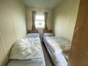 two beds in a small room with a window at Lovely 8 Berth Caravan At Southview Park Nearby Skegness Ref 33009v in Skegness