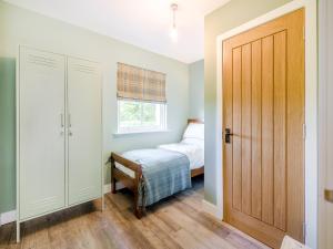 a bedroom with a bed and a wooden door at Auld Acquaintance Cottage in Dalswinton