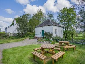 a group of picnic tables in front of a building at Auld Acquaintance Cottage in Dalswinton