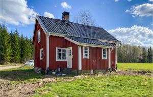 ein rotes Haus mit einem Dach auf einem Feld in der Unterkunft Nice Home In Tjurstorp With Kitchen 