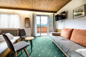 a living room with a couch and a balcony at Hotel Antholzerhof in Anterselva di Mezzo