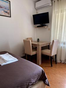 ein Schlafzimmer mit einem Tisch und Stühlen sowie einem TV in der Unterkunft Apartmani Stanojevic in Kotor