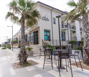 una caffetteria con sedie e palme di fronte a un edificio di Hotel Greta B&B a Rimini