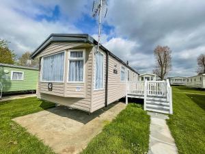 a tiny house in a yard with a porch at Beautiful Caravan With Decking And Free Wifi At Highfield Grange Ref 26740wr in Clacton-on-Sea