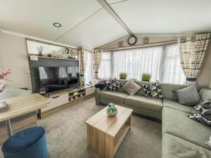 a living room with a couch and a tv at Beautiful Caravan With Decking And Free Wifi At Highfield Grange Ref 26740wr in Clacton-on-Sea