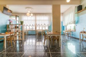 una sala da pranzo con tavoli, sedie e pareti blu di Hotel Greta B&B a Rimini
