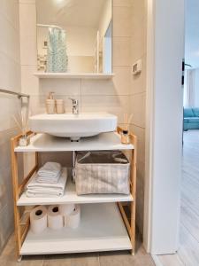 a bathroom with a sink and a shelf with towels at AZUR Apartment in Timişoara