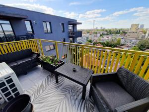 uma varanda com sofás, uma mesa e uma cerca amarela em AZUR Apartment em Timisoara