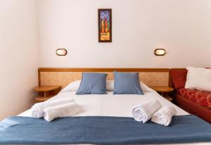 a bed with blue and white sheets and a red couch at Hotel Greta B&B in Rimini