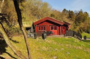 uma cabina vermelha com um alpendre num campo em Norsk Bjlkehus Med Fjordudsigt em Hobro