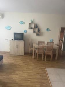 ein Wohnzimmer mit einem Tisch, Stühlen und einem TV in der Unterkunft Lozenetz Beach Apartments in Lozenets