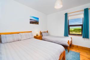 2 Betten in einem Zimmer mit Fenster in der Unterkunft Cottage 118 - Cleggan in Cleggan