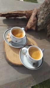 dos tazas de café sentadas en una bandeja de madera en Casa Prieteniei - camere - 3 km Piatra Neamț, en Piatra Neamţ