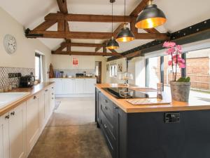 eine große Küche mit weißen Schränken und Holzbalken in der Unterkunft The Granary in Newport