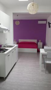 - une cuisine avec un lit rouge et un mur violet dans l'établissement Case vacanze Iris, à Uggiano la Chiesa