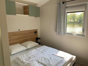 a small bedroom with a bed with a window at Camping Les Tourterelles in Rang-du-Fliers +78 photos