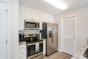 Una cocina con gabinetes blancos y un refrigerador de acero inoxidable. en Surfside 17 by Pristine Properties Vacation Rentals, en Mexico Beach