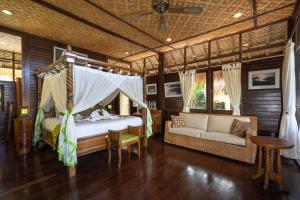 a bedroom with a bed and a couch in a room at Kupu Kupu Private Villa in Ubud