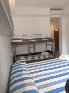 een slaapkamer met een stapelbed met blauwe en witte strepen bij Hotel Ambasciata in Riccione