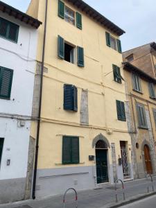 een geel gebouw met groene luiken op een straat bij Casa Centrale in Pisa