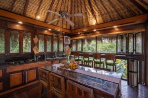 a kitchen with a center island with chairs and a ceiling at Kupu Kupu Private Villa in Ubud