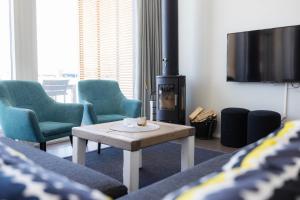 a living room with chairs and a table and a tv at Nallikari Holiday Village Villas in Oulu