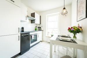 a kitchen with white appliances and a table with a vase of flowers at APARTMENTO Magdeburg - Zentral - 2 Zimmer - WiFi - Netflix in Magdeburg