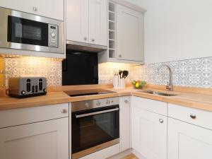 kuchnia z białymi szafkami, zlewem i kuchenką mikrofalową w obiekcie Cameron Fell Apartment Keswick w mieście Keswick