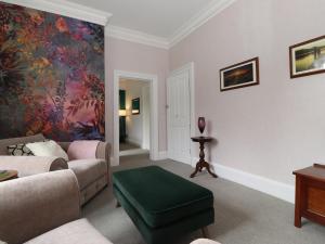 un soggiorno con divano e ottomana verde di Cameron Fell Apartment Keswick a Keswick