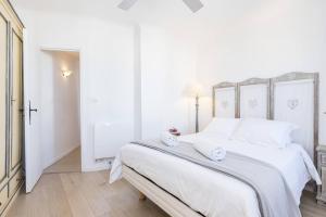 een witte slaapkamer met een groot bed met witte lakens bij Le Voeu - Appartement avec vue sur Nice in Nice