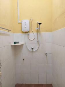 La salle de bains est pourvue d'une douche et d'un distributeur de savon sur le mur. dans l'établissement Inapan desa bukit papan, à Kuala Perlis