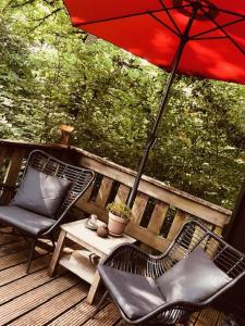een patio met 2 stoelen en een tafel met een parasol bij Chalet Woods in Durbuy