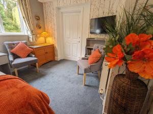 a living room with a vase with orange flowers in it at Foxhills of Shanklin in Shanklin