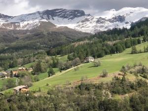 le champas في Enchastrayes: حقل أخضر مع جبال مغطاة بالثلوج في الخلفية