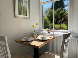 a wooden table with two chairs and a window at Bethby Beck Apartment Keswick in Keswick